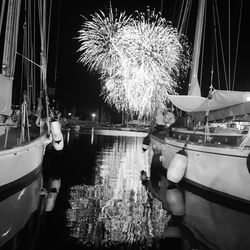 Boats moored at harbor against sky at night