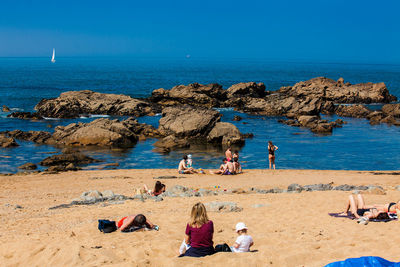 People on beach against clear blue sky