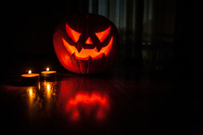 Close-up of illuminated tea lights and pumpkin on table