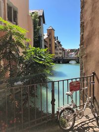 Bicycle by railing against buildings in city