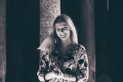 Portrait of smiling woman standing against wall