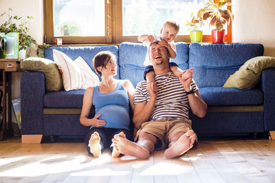 Rear view of friends sitting on sofa at home