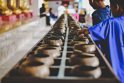 Rear view of boys walking by food containers in temple