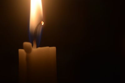 Close-up of lit candle in dark room