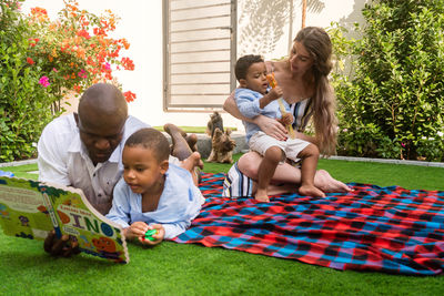 Mixed raced family sitting in the backyard together with a dog