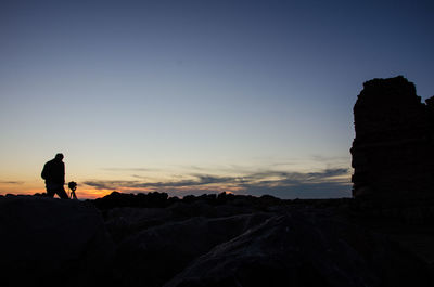 Silhouette man standing on cliff against sky during sunset