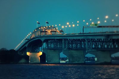 Illuminated bridge over river against sky