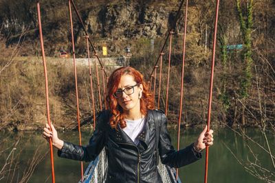 Portrait of beautiful young woman holding on a bridge