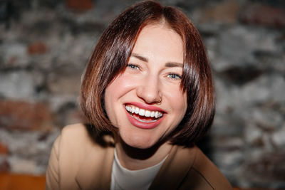 Close-up of a woman's bright, engaging smile against a textured backdrop