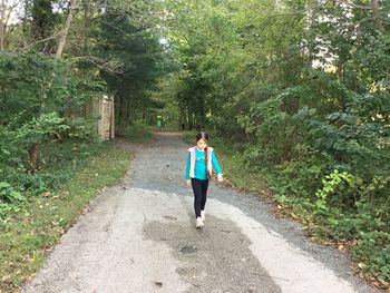 Full length of girl walking on road amidst trees