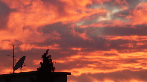 Low angle view of silhouette statue against orange sky