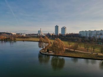 Bridge over river by buildings in city against sky