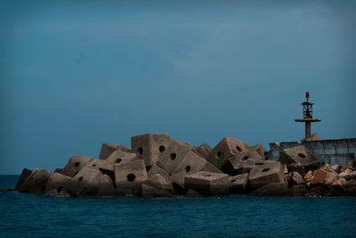 Rocks by sea against blue sky