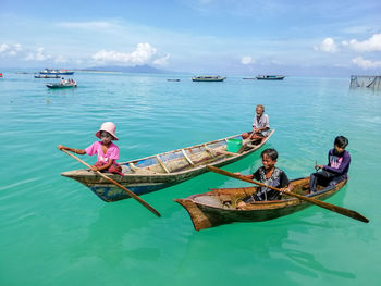 People on boat in sea against sky