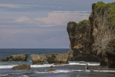 Scenic view of sea by cliff against sky