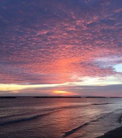 Scenic view of sea against dramatic sky during sunset