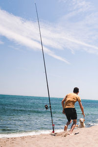 Rear view of men on beach against sky