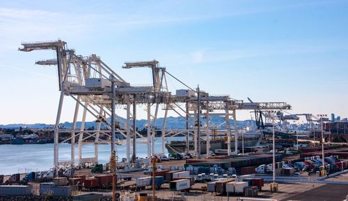 Cranes at harbor against sky