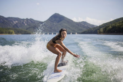 Side view of man splashing water against mountain range