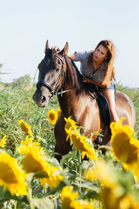 Close-up of young woman with yellow flowers on field