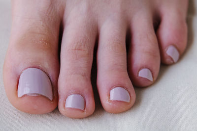 Close-up of female feet painted grey nail polish, self made pedicure at home.