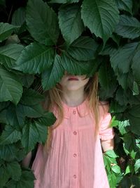 Girl hiding while standing by plants