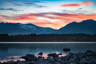 Scenic view of lake by mountains against sky during sunset