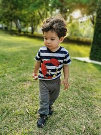 Cute baby boy walking on grassy land in park