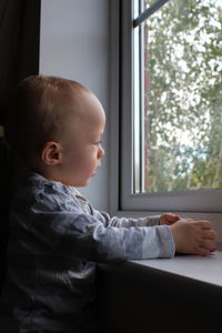 Boy looking through window at home