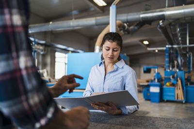 Inspector checking paperwork while working with colleague at industry