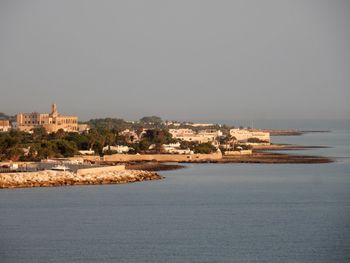 Buildings by sea against clear sky