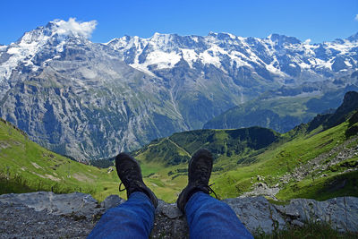 Low section of person on snowcapped mountains against sky