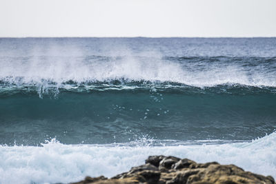 Close-up of waves in sea against clear sky