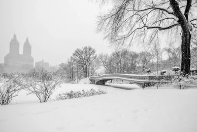 Snow covered field by building against sky