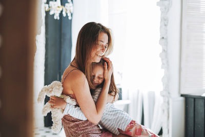 Young mother woman with long hair with little tween girl daughter in pajamas having fun in at home