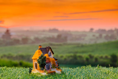 Traditional windmill on field against sky during sunset