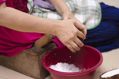 Midsection of woman shredding coconut