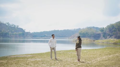 Friends standing on lake against sky