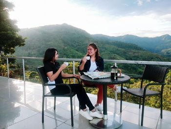 Woman sitting on table against mountains