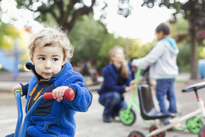 Boy looking away while riding tricycle on playground