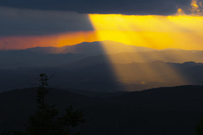 Scenic view of silhouette mountains against orange sky