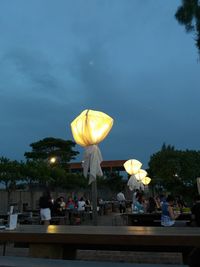 People at illuminated restaurant against sky at dusk