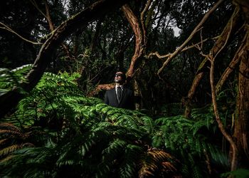 Full length of young man standing by tree in forest