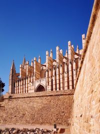 Low angle view of old sandy cathedral against clear blue sky