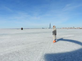 Rear view of woman walking on frozen sea against sky