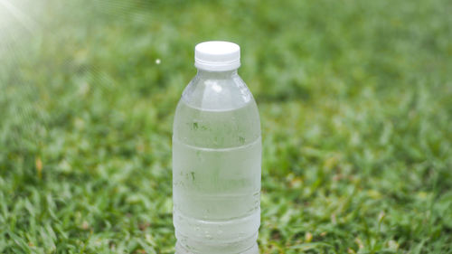 Close-up of glass bottle on field