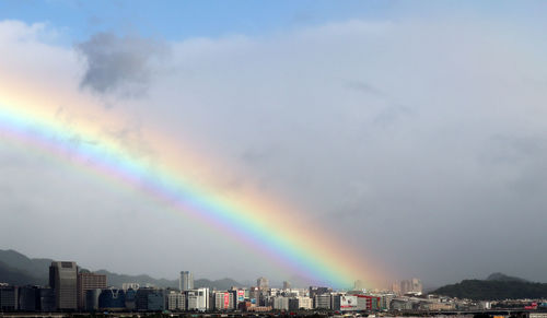 Rainbow over city against sky