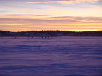 Scenic view of frozen lake against sky during sunset