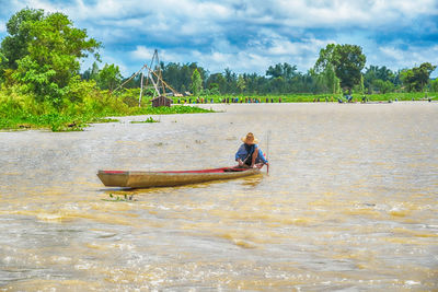 Man in boat on river against sky