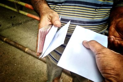 Cropped image of man giving envelope to friend